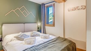 Una cama bien hecha con sábanas blancas y una manta decorativa de estampado verde.