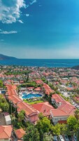 Un complejo turístico frente al mar con edificios de techo rojo y una piscina central.