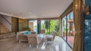A spacious lobby with a beige sofa set, a white coffee table, and a small round table. A staircase is visible on the left, leading to an upper floor. - Ölüdeniz Turquoise Hotel (Fethiye)