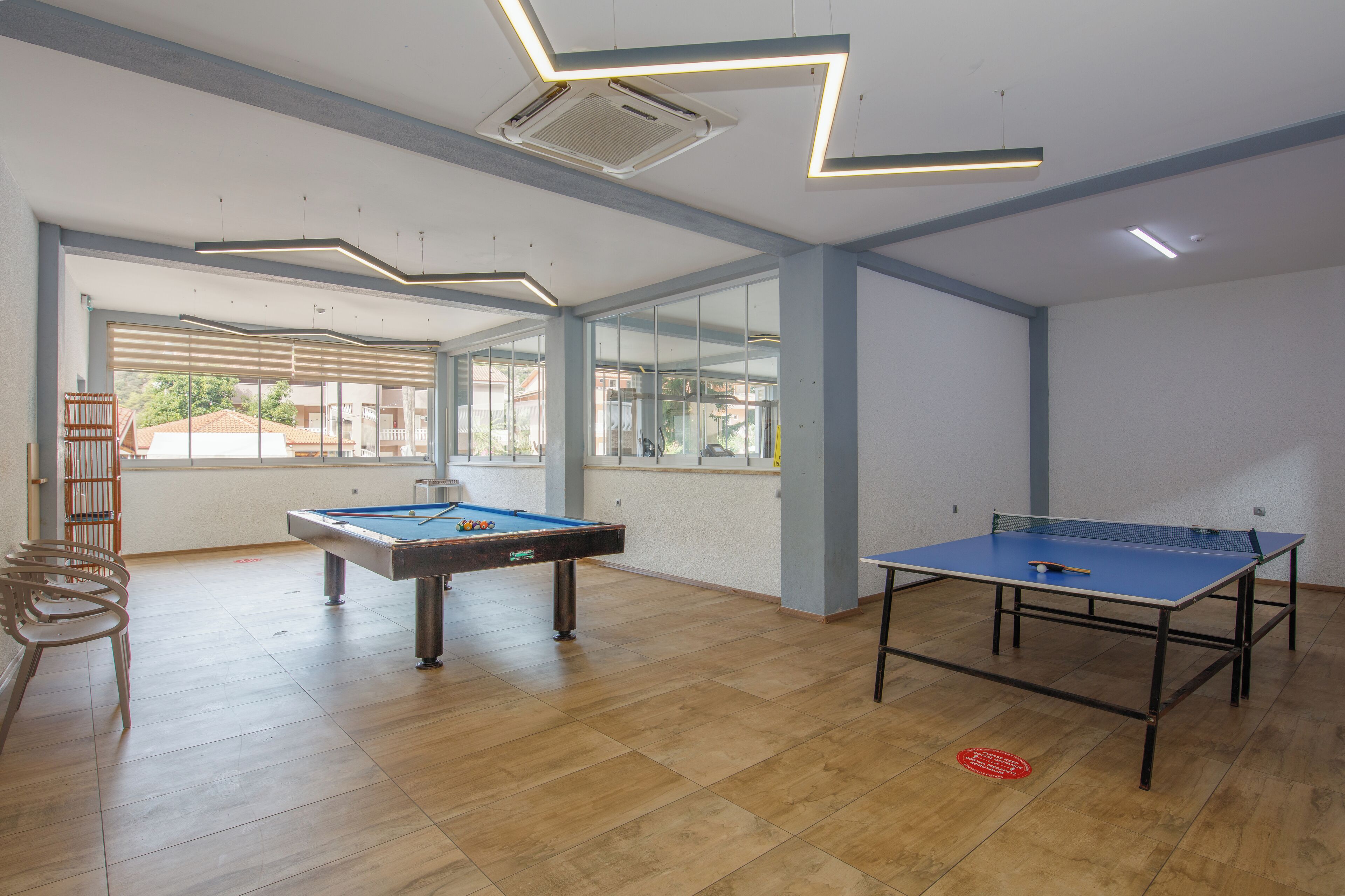 A spacious room with a pool table, a ping pong table, and a seating area with chairs.