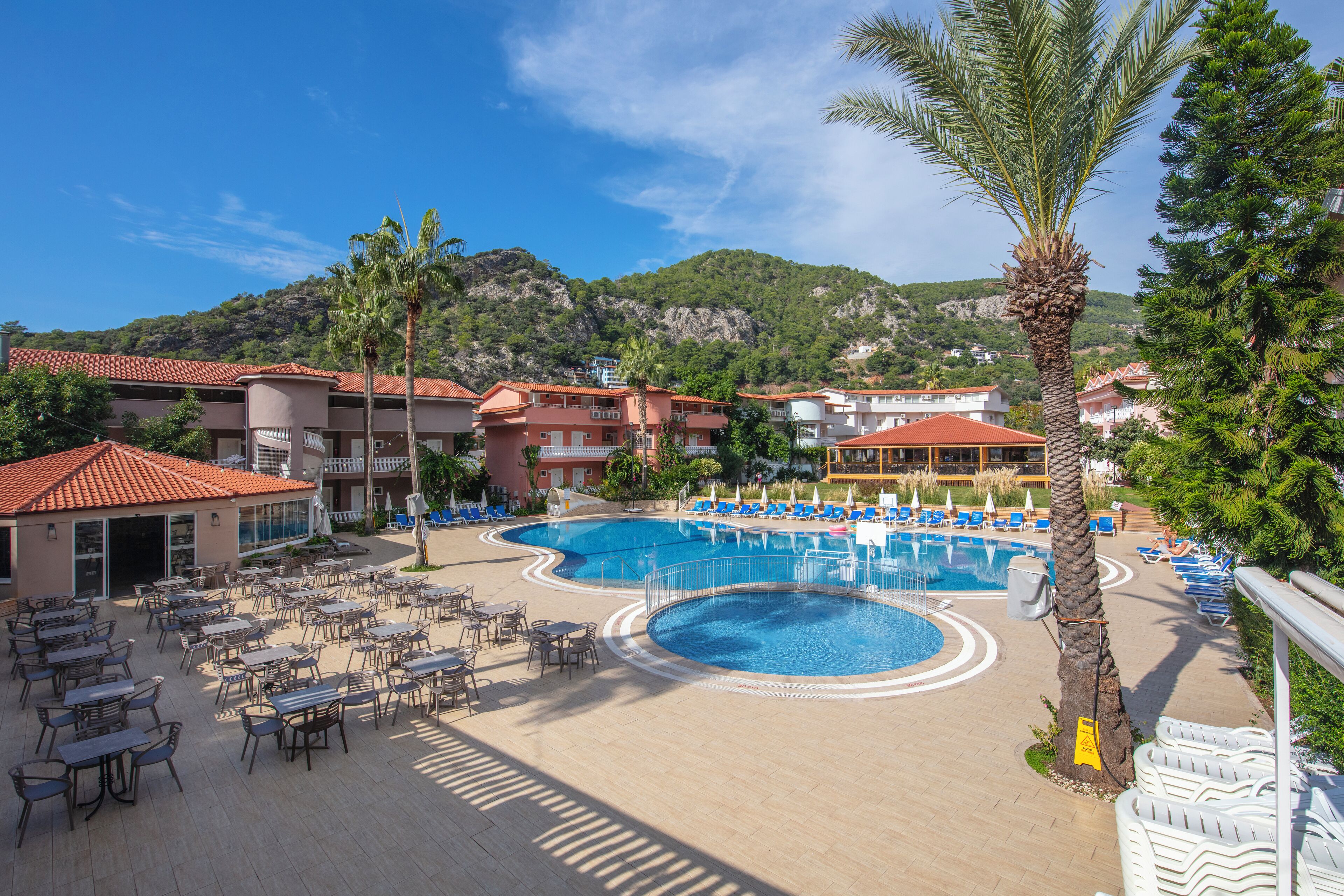 A resort with a large pool, outdoor seating, and mountain views.