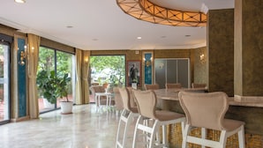 A spacious dining area with a large table and multiple chairs, a decorative ceiling light, and large windows with curtains. - Ölüdeniz Turquoise Hotel (Fethiye)