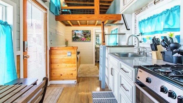 Une cuisine de taille réduite, avec des meubles de rangement en bois, une cuisinière et un évier.