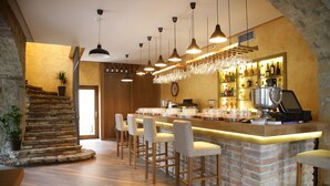 A bar area with a brick counter, bar stools, hanging lights, and a wine rack. - Garni Hotel Chicha - Winery Skrbic (Belgrade)