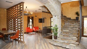 A dining area with a wooden wine rack, red chairs, a table, and a stone staircase. - Garni Hotel Chicha - Winery Skrbic (Belgrade)
