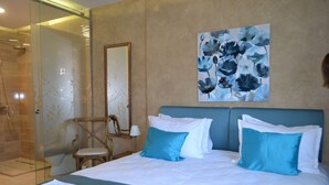 A hotel room with a bed, a chair, a shower, and a painting on the wall. - Garni Hotel Chicha - Winery Skrbic (Belgrade)