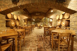 Uma adega com barris de madeira, paredes de pedra e mesas e cadeiras de madeira.