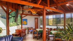 A spacious room with wooden beams, a green table, and chairs. - Village Paraiso Hotel (Florianópolis)