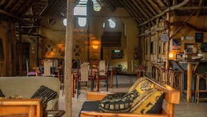 A rustic interior with wooden furniture, a thatched roof, and a cozy seating area. - Turtle Cove Lodge and Yoga Shala (Tofo)