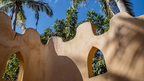 A view of palm trees against a clear sky, with a curved architectural structure in the foreground. - Turtle Cove Lodge and Yoga Shala (Tofo)
