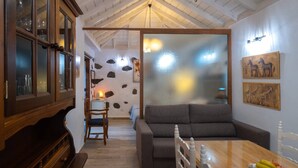 A cozy room with a wooden cabinet, a sofa, a dining table with fruit, and a wall with animal paintings.