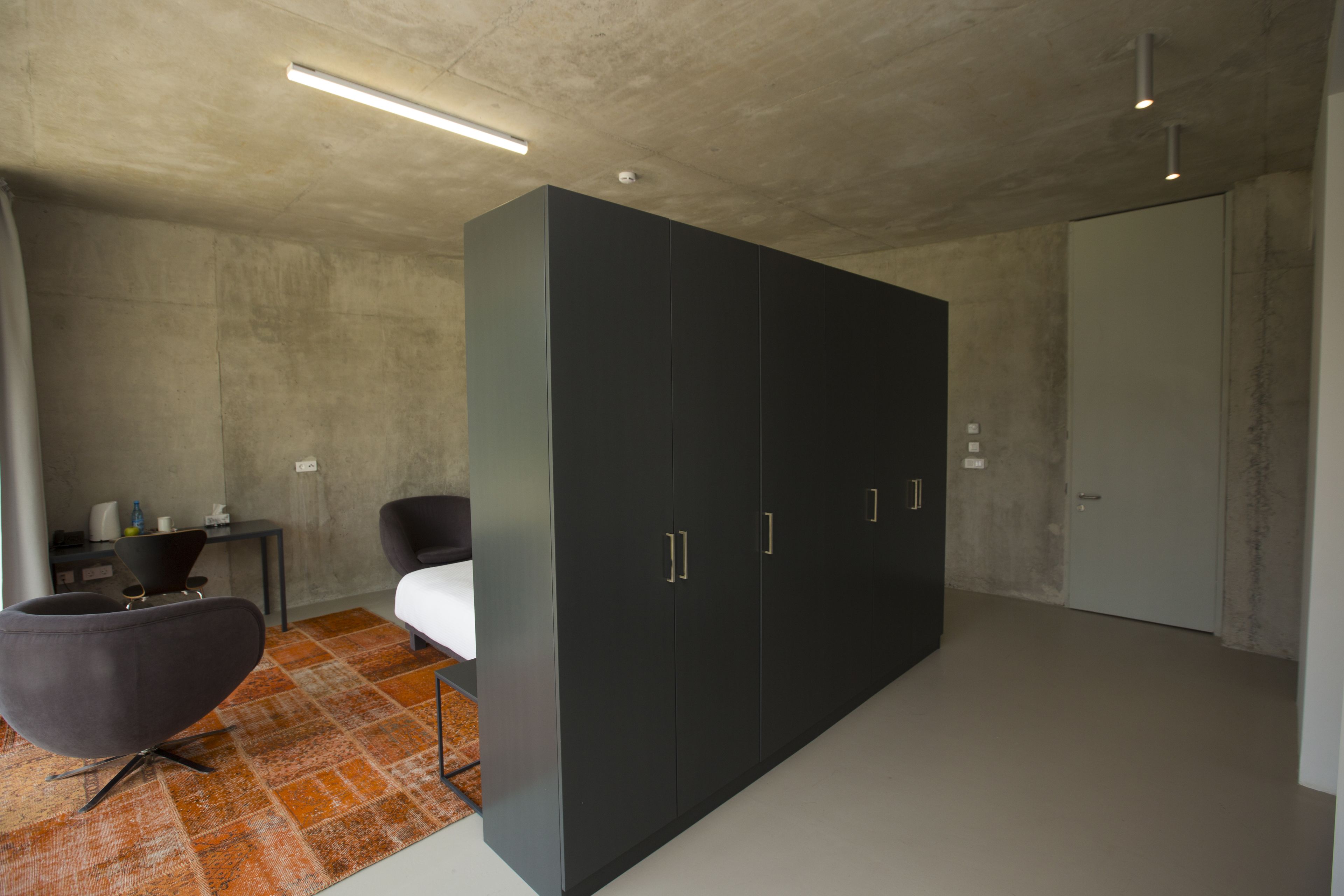 A modern bedroom with a large wardrobe, a bed, a chair, and a small table.