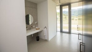 Un baño moderno con un ventanal grande, un lavabo, un espejo y un perchero para toallas.