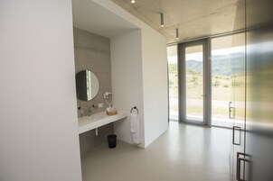 Un baño moderno con un ventanal grande, un lavabo, un espejo y un perchero para toallas.