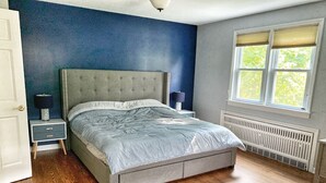 Una camera da letto con un letto, comodini, una finestra e un termosifone.
