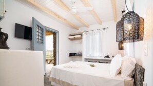 A bedroom with a bed, a TV, a ceiling fan, and a decorative light fixture.