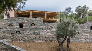 A stone building with a wooden structure on top, surrounded by trees and a clear sky.