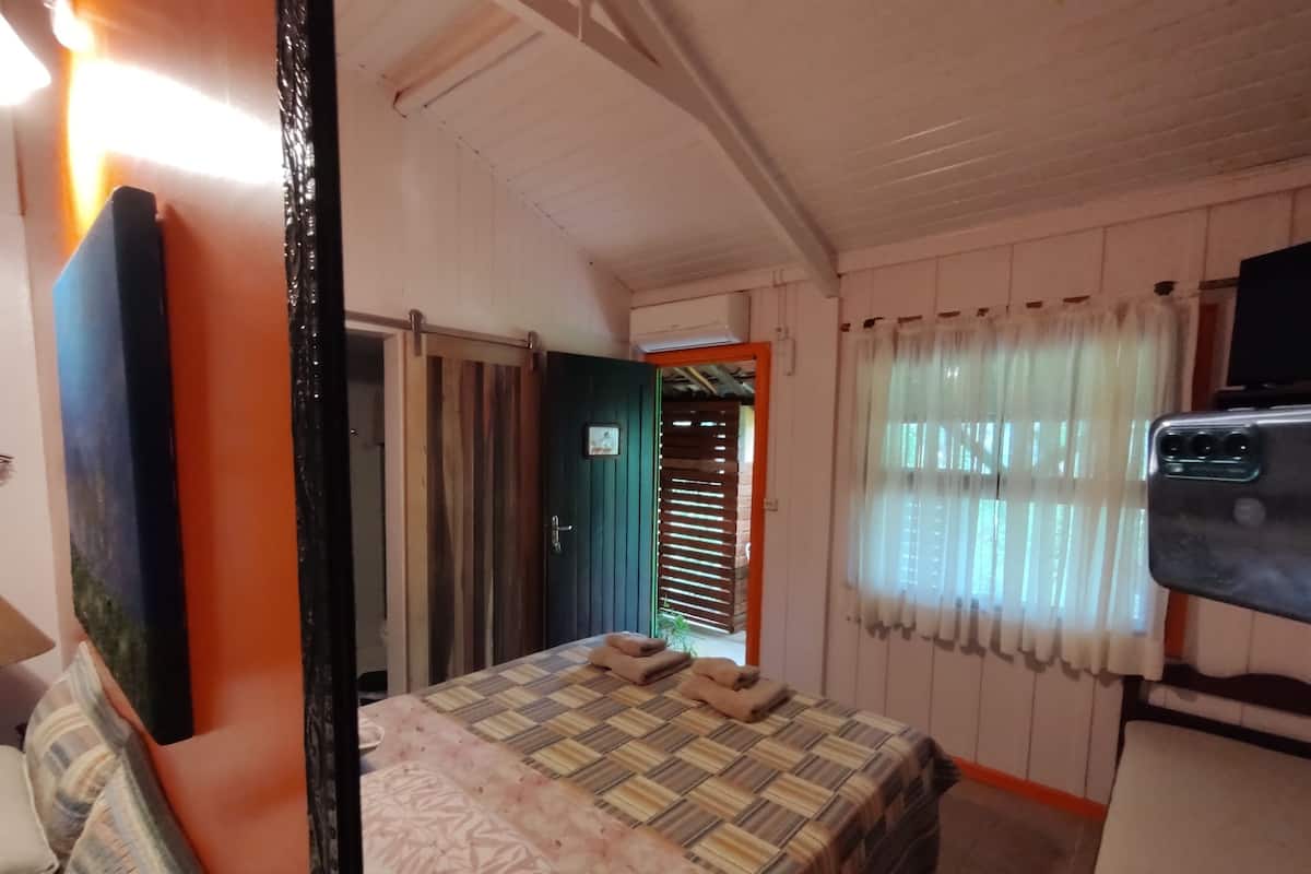 A hotel room with a bed, a desk, a chair, a television, and a window with curtains.