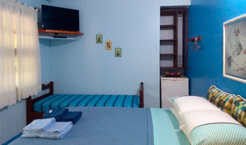 A bedroom with a bed, a TV, a small desk, and a wardrobe.
