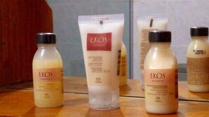 Cuatro botellas de productos EKOS sobre una superficie de madera.