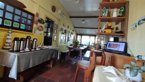 Un restaurante acogedor con muebles de madera, piso de baldosas y una computadora portátil sobre una mesa.
