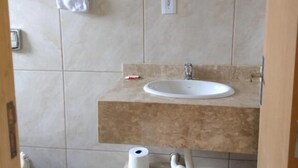 A bathroom with a sink, a towel rack, a toilet, and a trash bin. - Pousadas Mafra (Mafra)