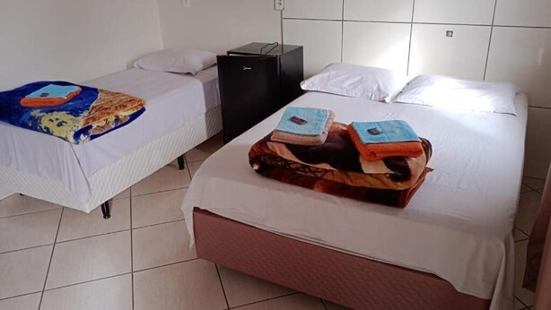 A hotel room with two beds, a small desk, and a tiled floor. - Pousadas Mafra (Mafra)