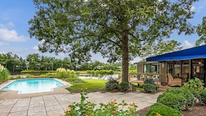 Un jardin à l’arrière de la maison avec une piscine, un patio couvert et un jardin bien entretenu.