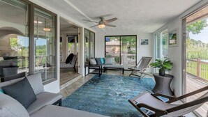 Un balcon spacieux doté d’un ventilateur de plafond, d’un tapis bleu à motifs et d’un coin salon avec un canapé et des fauteuils.