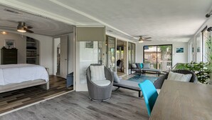Une pièce spacieuse comprenant un lit, un fauteuil en osier, un canapé et une table à manger.