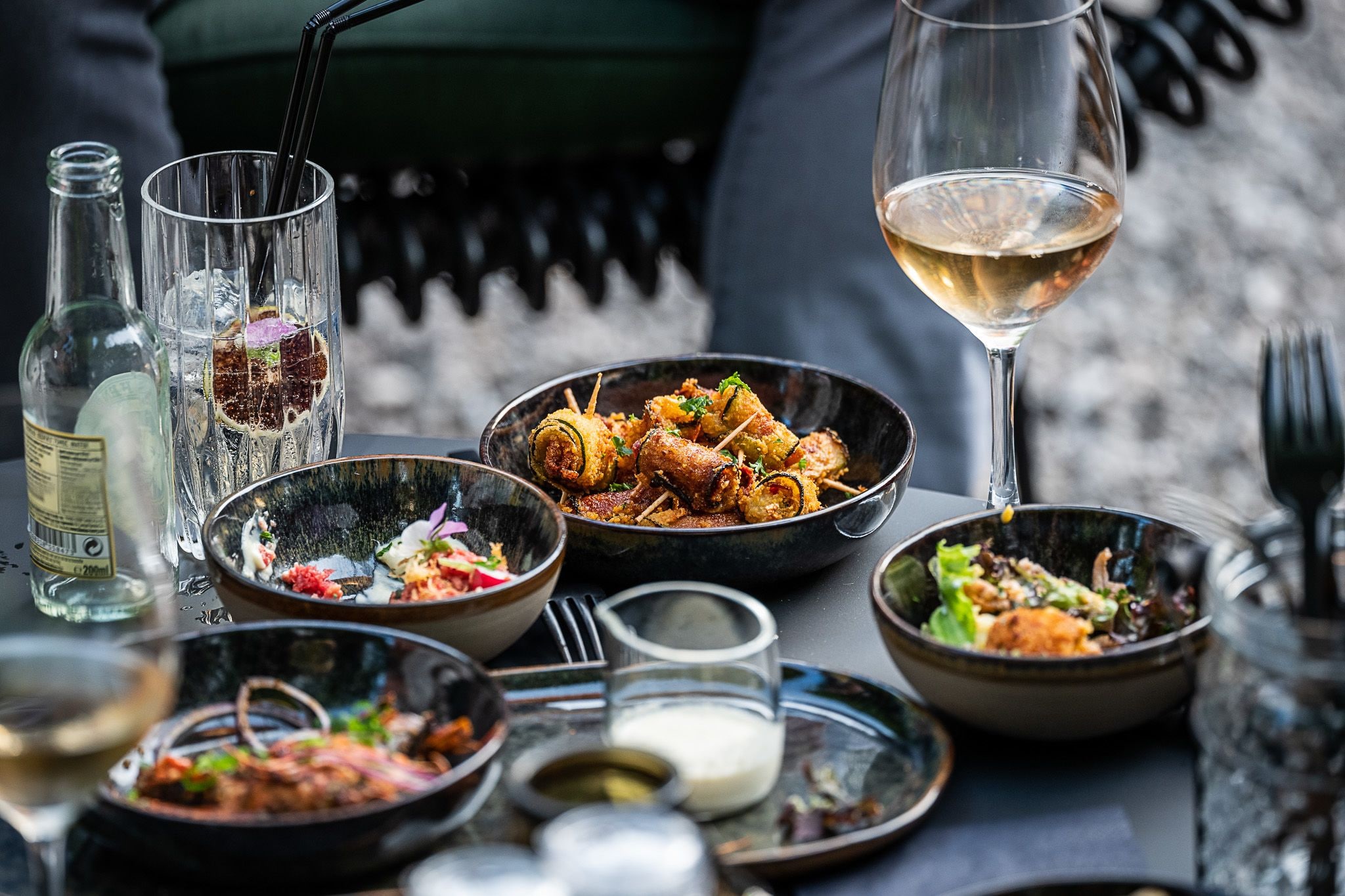 Una mesa dispuesta con diferentes platos, vasos y botellas, indicando una experiencia culinaria.