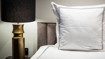 Ein Bett mit einem weißen Kopfkissen und einer schwarzen Lampe mit Messingsockel.