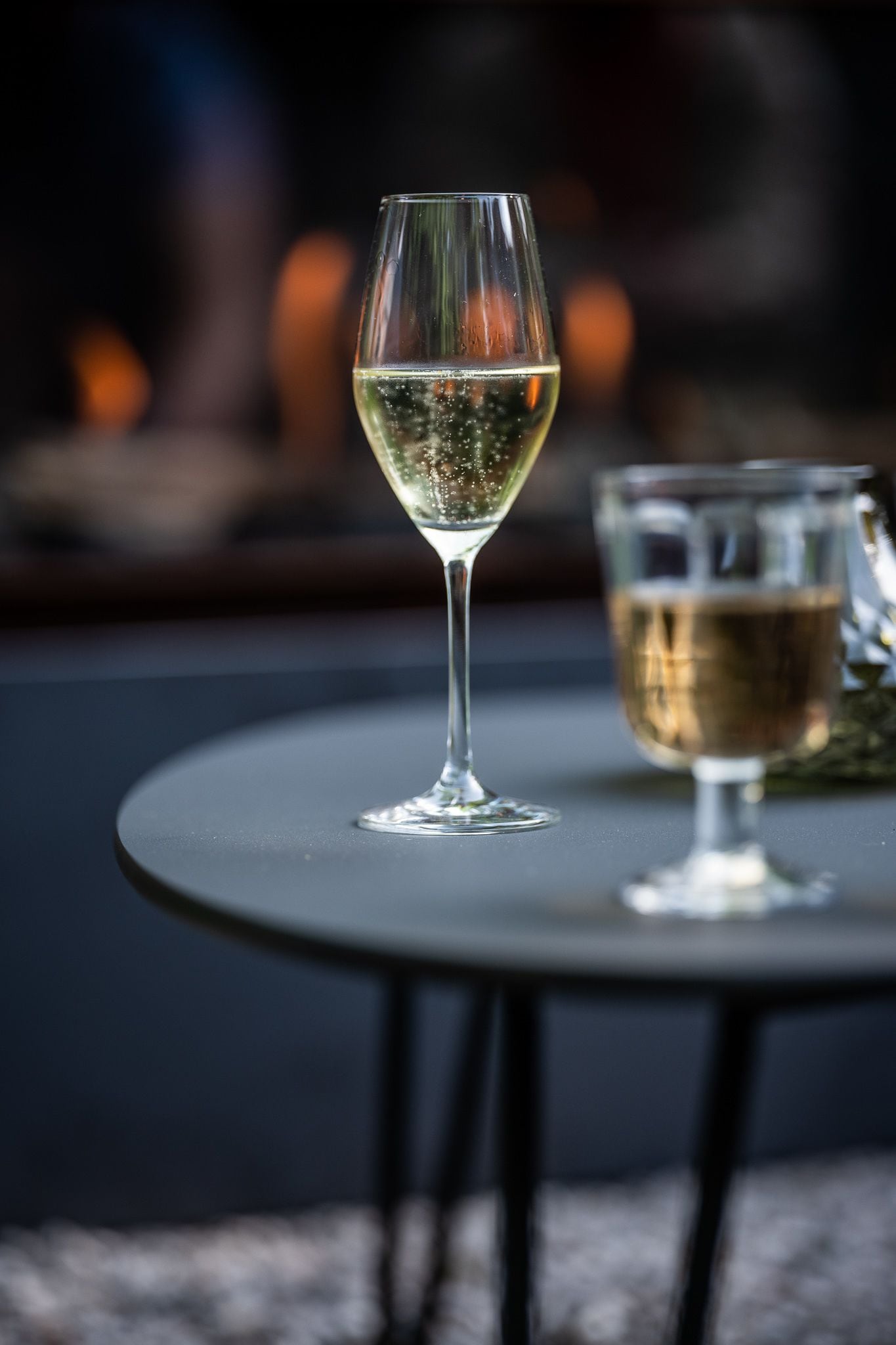 A glass of white wine on a round table with a blurred background.