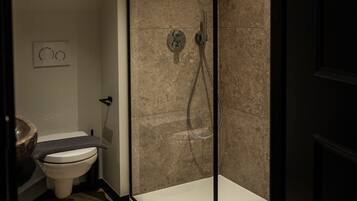 A modern bathroom with a glass-enclosed shower, a toilet, and a bathtub.
