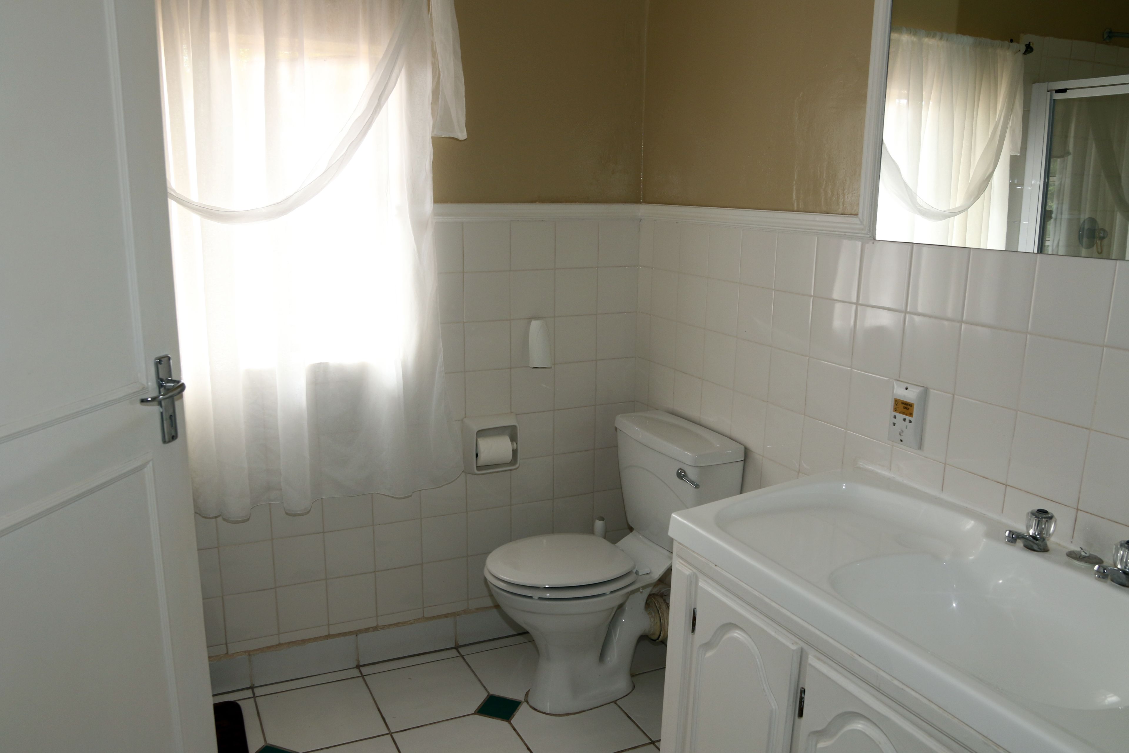 Un baño con inodoro, lavamanos y espejo.
