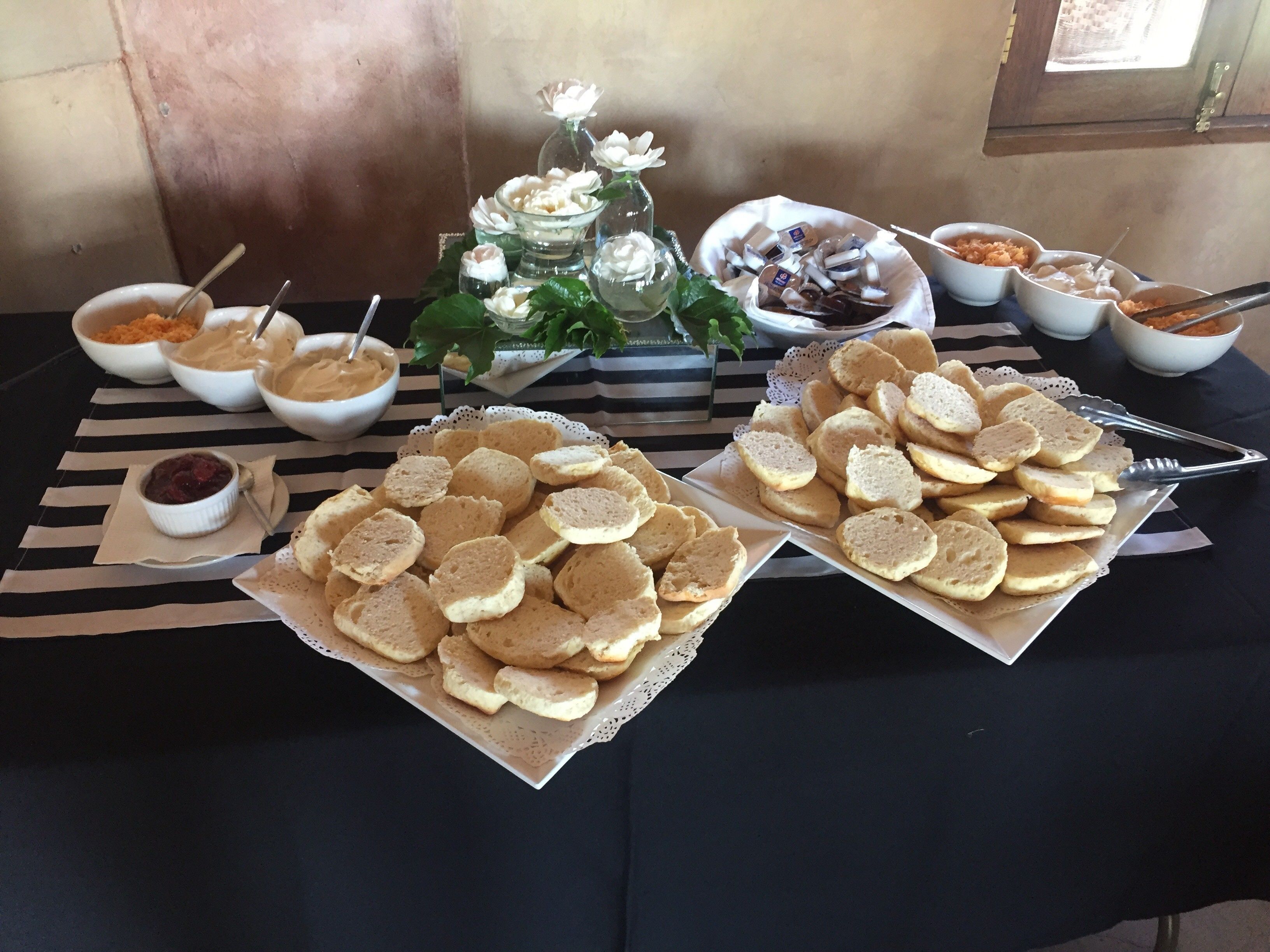 Ein Buffet mit verschiedenen Speisen, darunter Kekse, Dips und einer dekorativen Tischmitte.