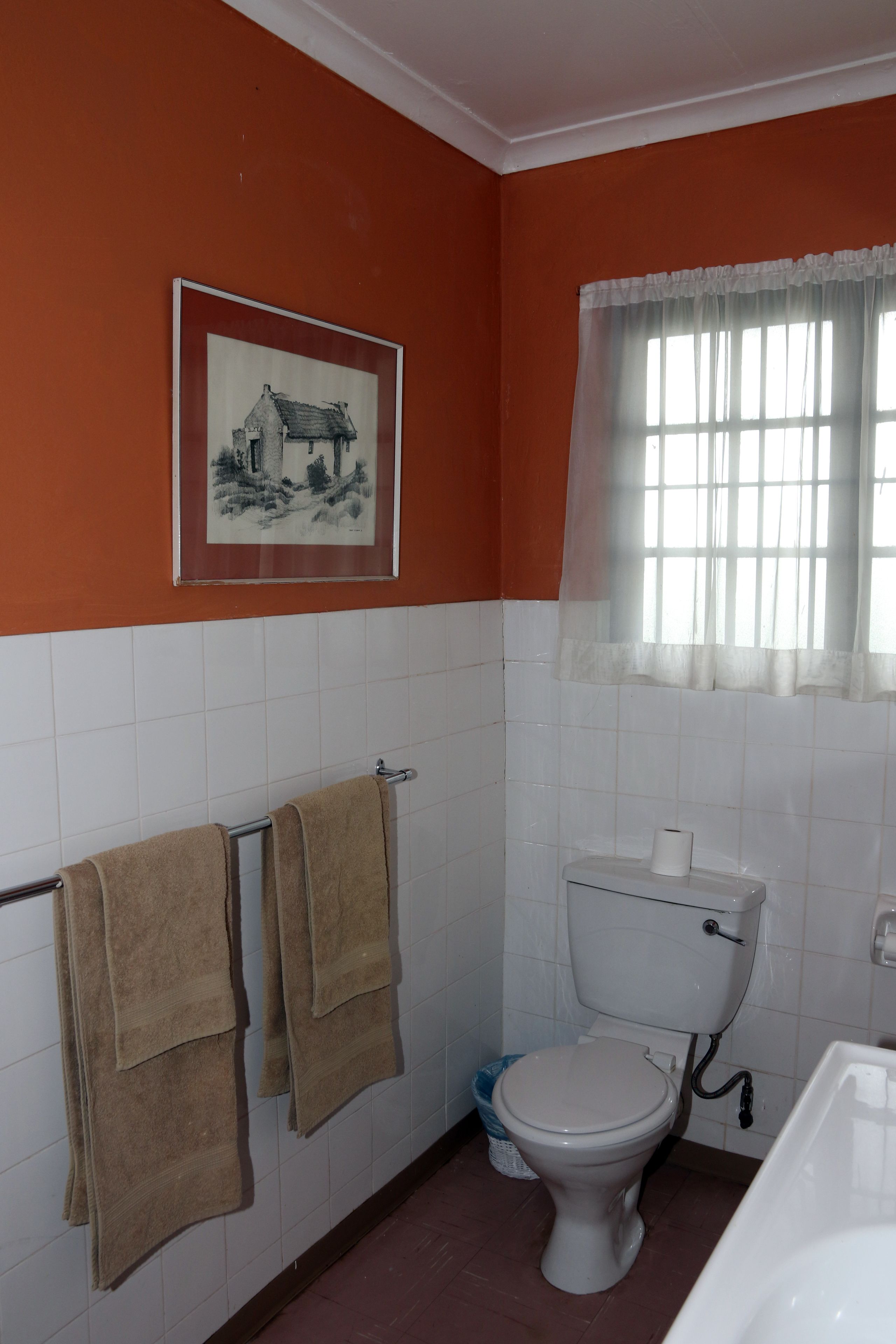 A bathroom with a toilet, sink, and a framed picture on the wall.