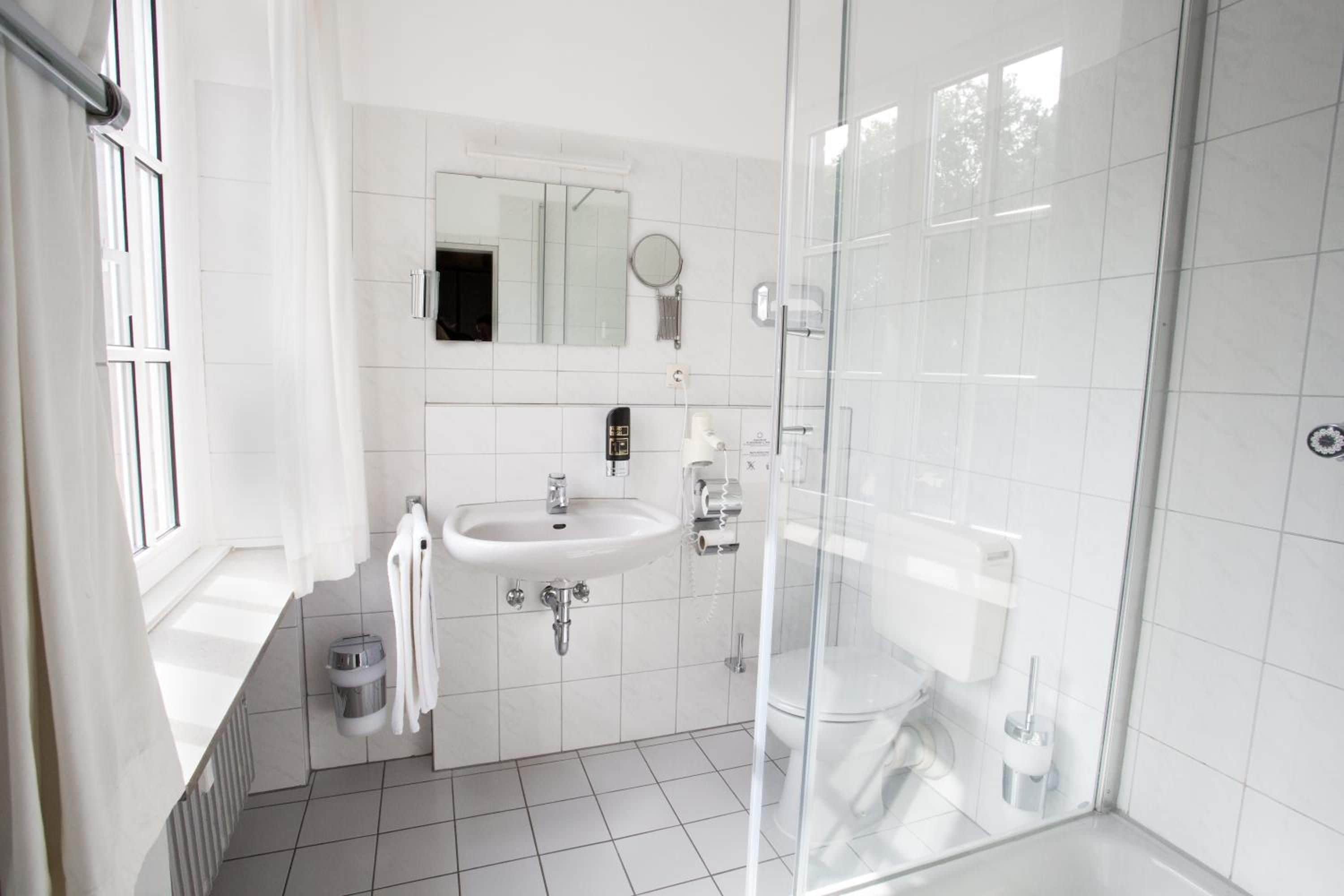 A modern bathroom with a glass shower enclosure, a white sink, and a mirror above it.