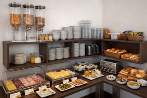 Disposição de buffet com diversos alimentos, utensílios e utensílios de servir.