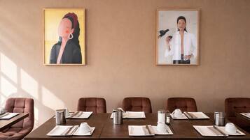 A conference room with a long table, brown chairs, and framed artwork on the wall.