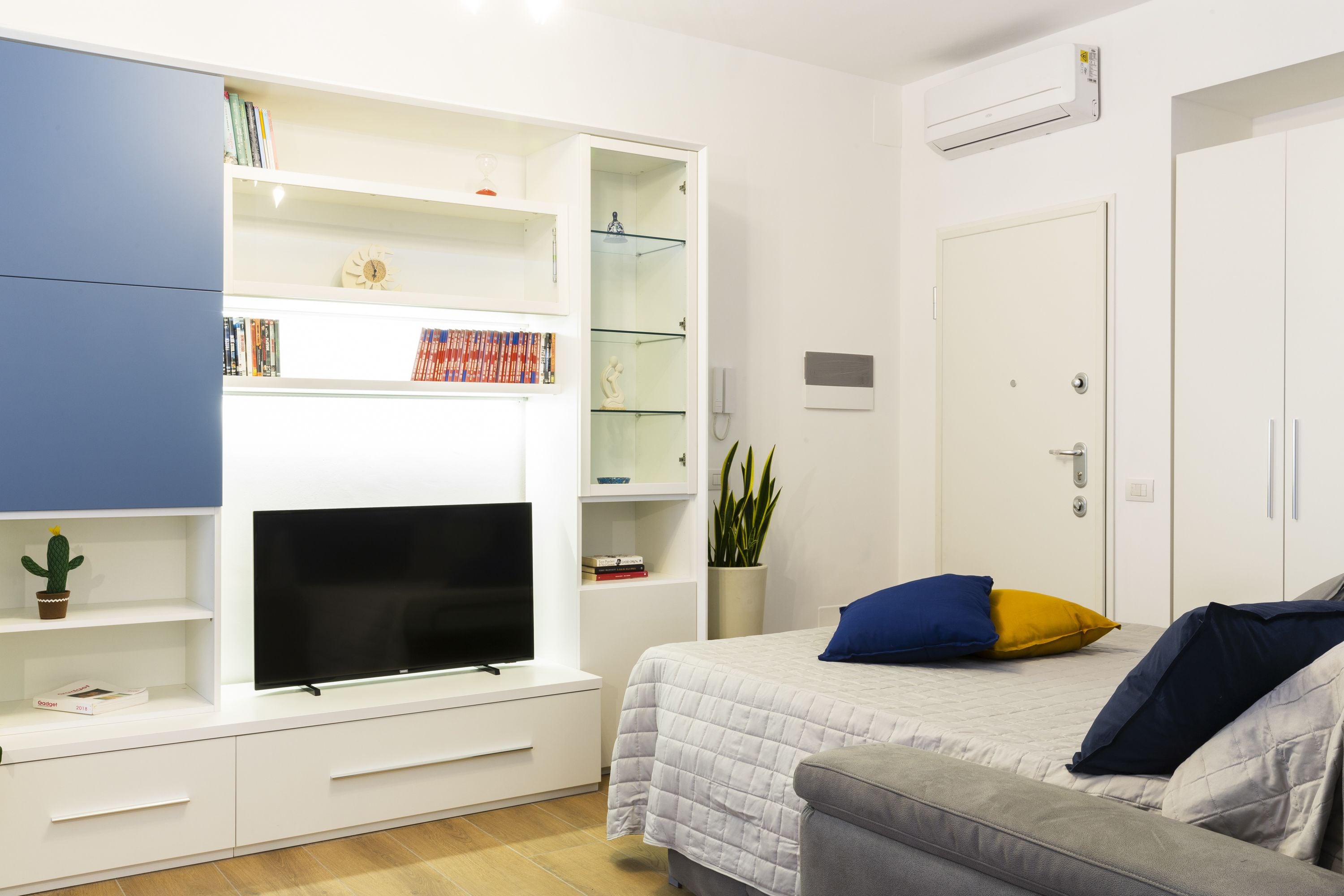 A modern bedroom with a bed, a TV, a bookshelf, and a wardrobe.