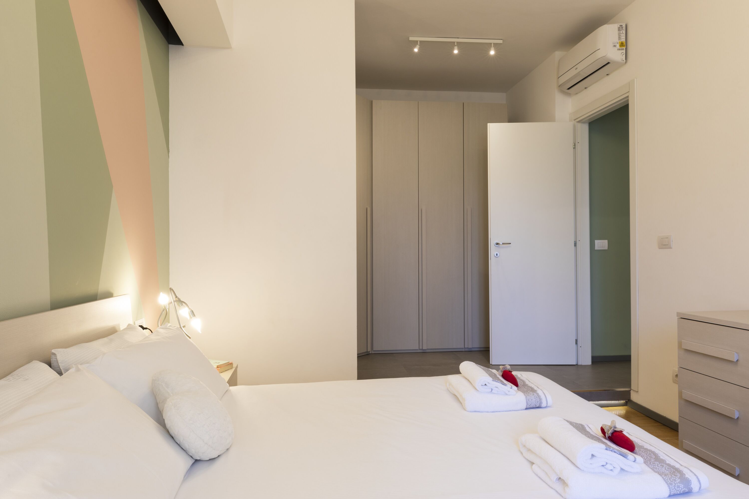 Habitación de hotel ordenada con cama, mesita de noche, escritorio y armario.