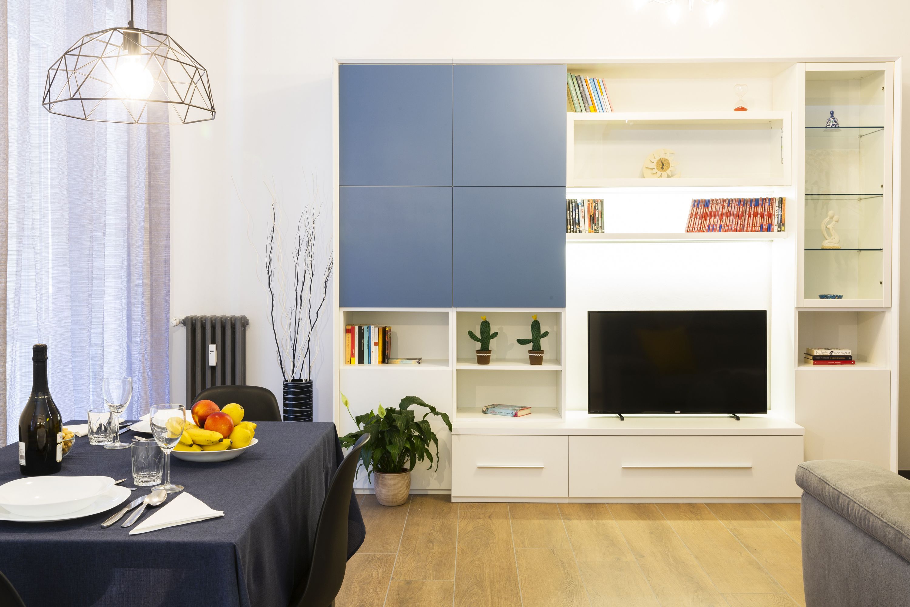 Una sala moderna con comedor, televisor de pantalla plana y estantería.