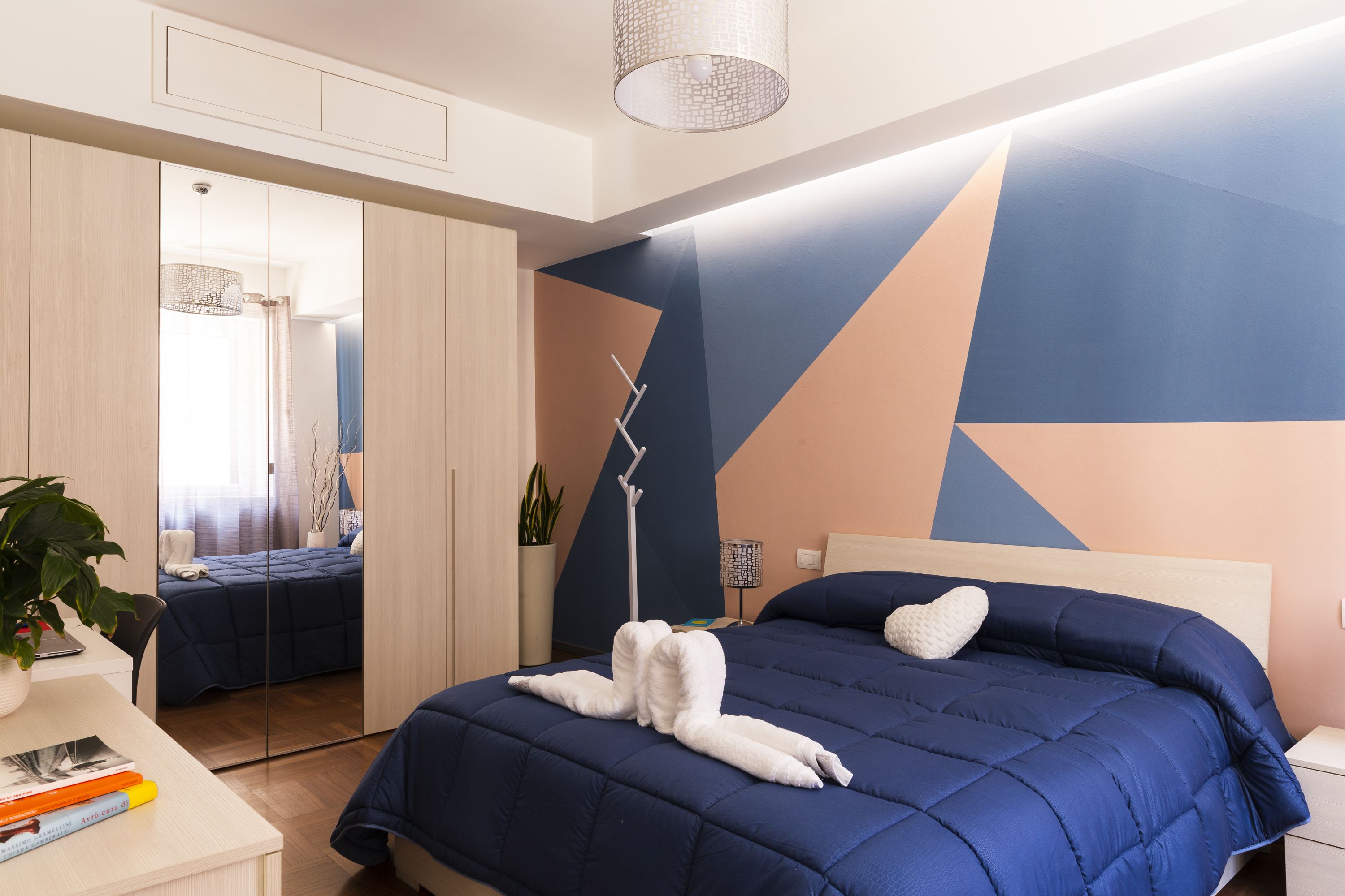 Un dormitorio moderno con una cama grande, una mesita de noche con lámpara y un espejo.