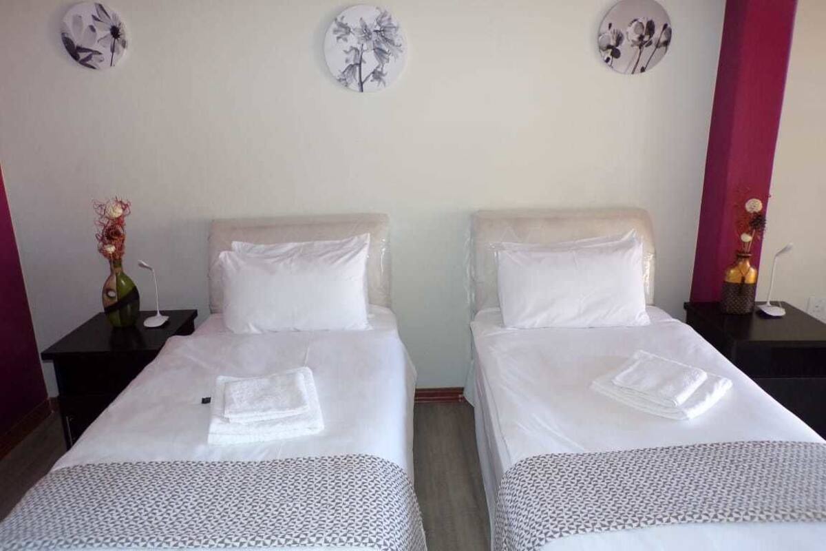 Une chambre d’hôtel avec deux lits, une table de chevet avec un vase et des éléments de décoration murale.