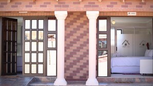 Entrada de un hotel con techo de tejas, fachada de ladrillo y puerta de cristal que da al interior.