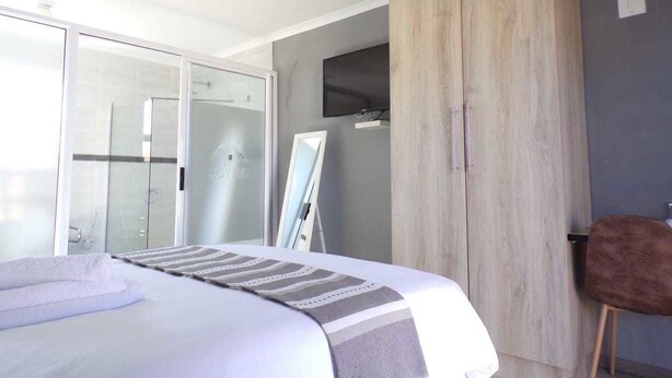 Un dormitorio con cama, armario, televisor y silla.