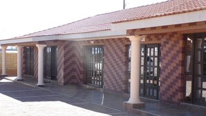 Un edificio con techo de tejas, columnas y ventanas con rejas.