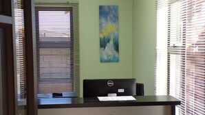 Un mostrador de recepción con una computadora Dell, un letrero que ofrece descuento para suscriptores de revistas y un cuadro en la pared.