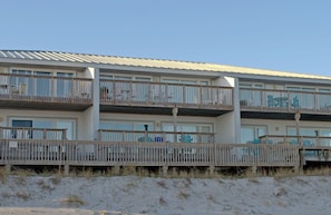 A beachfront hotel with multiple balconies, a sandy beach in front, and a clear sky. - Ocean Potion - Oceanfront Queen's Grant Condo with Amazing Views! (Topsail Beach)